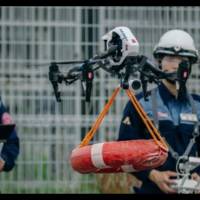 Officials from the Yaizu Crisis Management Division guide a drone that has been fitted with a life buoy to the location of a person in need of help in the ocean as part of an emergency drill. | COURTESY OF YAIZU CITY CRISIS MANAGEMENT DIVISION
