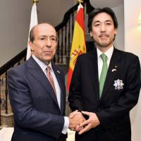 Spanish Ambassador Gonzalo de Benito (left) shakes hands with Minoru Kiuchi, former state minister for foreign affairs and a member of Japan-Spain Parliamentary Friendship League, after presenting him with an Order of Civil Merit at the ambassador\'s residence on Dec. 12. | COURTESY OF THE SPANISH EMBASSY
