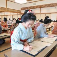 Maiko (apprentice geisha) transcribe a Buddhist sutra Wednesday at Daikakuji Temple in the city of Kyoto. The transcribing was part of a training program to learn more about the culture and history of the country\'s ancient capital. | KYODO