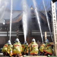 Jets of water are showered over the main hall of Jindaiji Temple in Chofu, western Tokyo, on Friday. The training exercise was conducted to mark Cultural Property Fire Prevention Day, which was established after a fire damaged Horyuji Temple in Nara Prefecture on Jan. 26, 1949. | KYODO