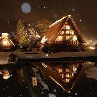 Snow-covered gasshō-zukuri (praying hands) farmhouses are illuminated in the town of Shirakawa-go, Gifu Prefecture, a registered UNESCO World Heritage site, on Sunday. The illumination event will also take place on Jan. 28, Feb. 4 and Feb. 12 between 5:30 p.m. to 7:30 p.m., with visitors limited to 900 people per occasion. | KYODO