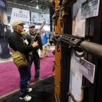John Chadwick (left) and his son Joshua of Triple J Firearms in Magnolia, Texas, look over Remington rifles and shotguns during the annual SHOT Show in Las Vegas, Nevada, in January 2013. | REUTERS