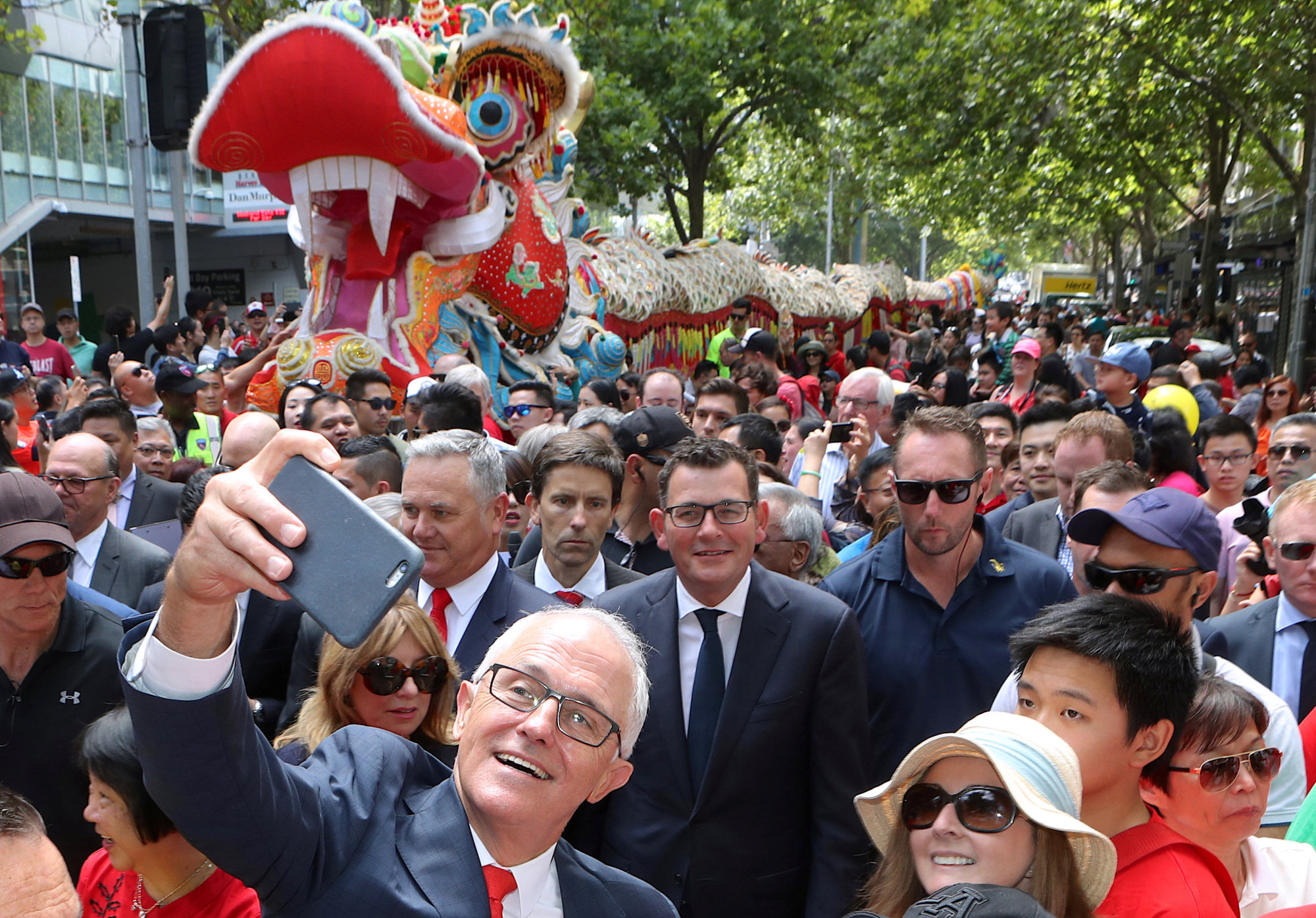 Australian Prime Minister Malcolm Turnbull takes a selfie as he walks with Victorian Premier Daniel Andrews and members of the public during a parade as part of the Chinese New Year Festival in Melbourne, Australia, Sunday. | AAP / DAVID CROSLING / VIA REUTERS