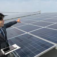An employee of Daiwa House Industry Co. presents solar panels on the roof of the firm\'s new self-powered office building in the city of Saga. | KYODO
