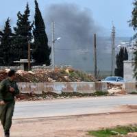 A Kurdish fighter evacuates Tuesday following Turkish artillery bombardment near the Afrin crossing in the northern Syrian region, after Syrian pro-government forces entered the region. | AFP-JIJI