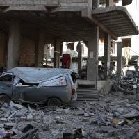 A picture taken Wednesday shows a damaged make-shift ambulance vehicle among rubble in a heavily damaged street in the rebel-held enclave of Hamouria in eastern Ghouta near Damascus, following a reported regime airstrike. | AFP-JIJI