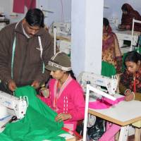 Mohammad Riyaz, who set up a solar-powered garment manufacturing unit in the village of Kamlapur in Uttar Pradesh, works with one of the 25 women stitching clothing on Jan. 9. | THOMSON REUTERS FOUNDATION