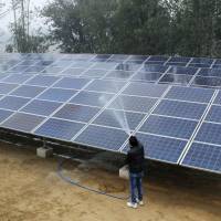 Solar panels being washed at a solar minigrid installation in Kamlapur on Jan. 9. | THOMSON REUTERS FOUNDATION/MANIPADMA JENA