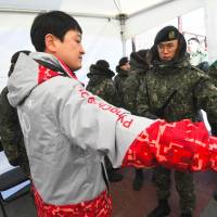 South Korean soldiers inspect a visitor at a security checkpoint as they replace security guards showing symptoms of norovirus at the Gangneung Ice Arena in Gangneung on Tuesday. | AFP-JIJI