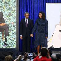 Former U.S. President Barack Obama and former first lady Michelle Obama hold hands between their portraits during an unveiling ceremony at the Smithsonian\'s National Portrait Gallery in Washington Monday. | REUTERS