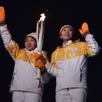 Jong Su Hyon of North Korea and Park Jong-ah of South Korea hold the Olympic flame before the lighting of the cauldron during the opening ceremony of the Pyeongchang Winter Olympic Games at Pyeongchang Stadium on Friday. | AFP-JIJI