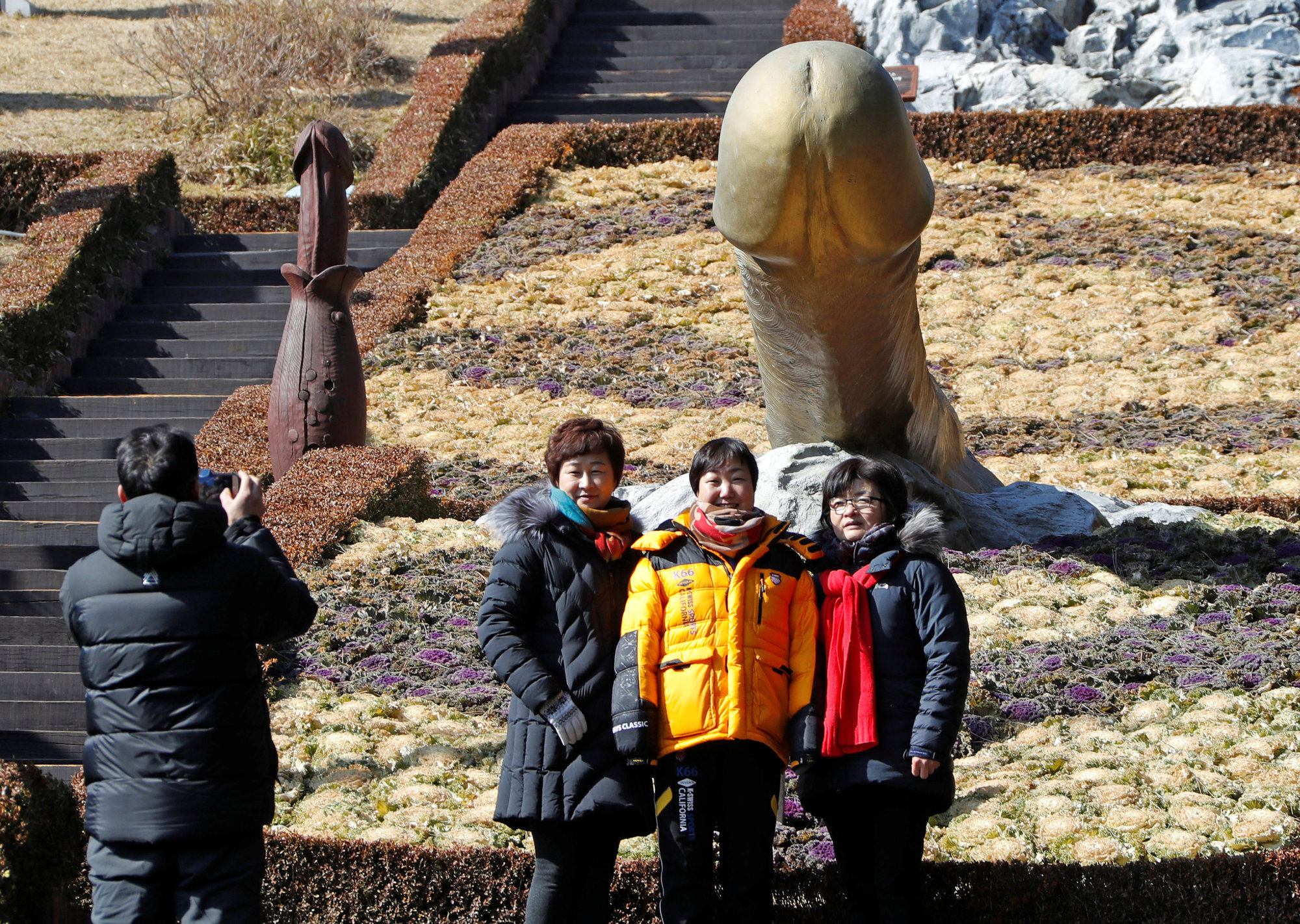 Tourists pose near a statue in Haeshindang Park, known euphemistically as the 'Penis Park,' on Monday in Sinnam, South Korea. The park is a shrine to fertility, dedicated to the legend of a local girl who died a virgin. | REUTERS