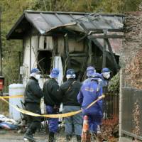 Police officers on Sunday investigate the rubble of a house that burned down the previous day in Inzai, Chiba Prefecture. | KYODO