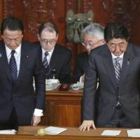 Prime Minister Shinzo Abe (right) and Finance Minister Taro Aso bow on Wednesday night after Lower House approved a record &#165;97.71 trillion budget for fiscal 2018. | KYODO