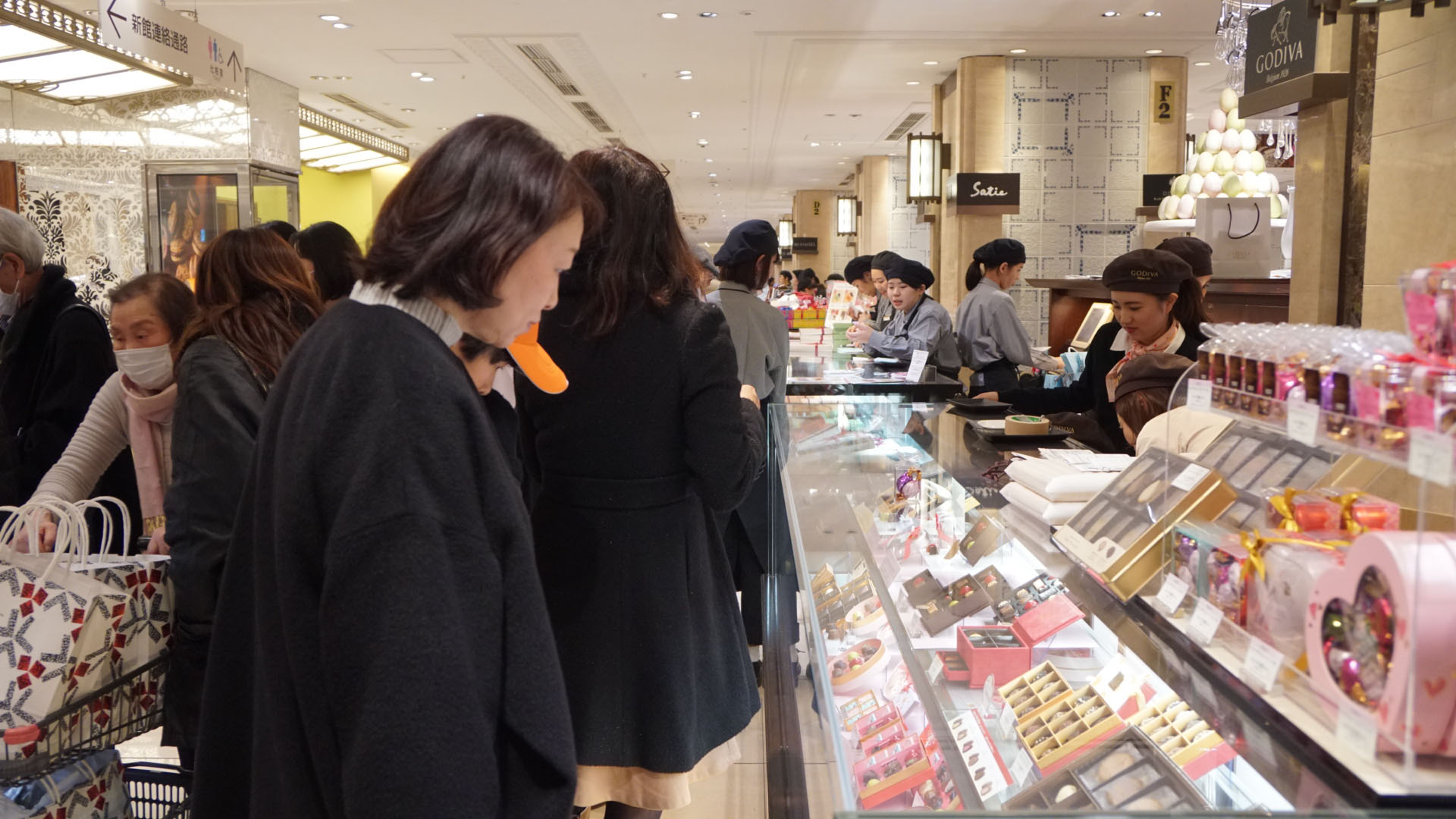 Customers look at chocolates in Godiva showcases at the Mitsukoshi Nihonbashi Main Store in Chuo Ward, Tokyo, on Saturday. | CHISATO TANAKA