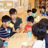 Children eat snacks at a private day care center in Funabashi, Chiba Prefecture, in July 2016. | KYODO