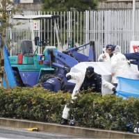 Police inspect the area where a construction vehicle fatally struck students and teachers from a school for children with impaired hearing in Osaka Thursday. The accident killed a student and injured four other people. | KYODO