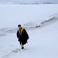 A man on Friday walks past the first omiwatari (crossing of the gods) seen at Lake Suwa in Nagano Prefecture since 2013. | KYODO