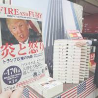 Copies of the Japanese translation of \"Fire and Fury: Inside the Trump White House,\" are stacked in front of a photograph of Trump Tower at a bookstore in Chiyoda Ward, Tokyo, on Friday for its debut in Japan. | KYODO