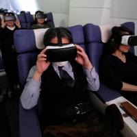 Visitors wear virtual reality goggles as they \"travel\" with First Airlines, a first-class airline experience facility in Tokyo, earlier this month. | REUTERS