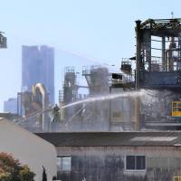 Firefighters hose down an chemical factory in Yokohama after a fire broke out there Monday. | KYODO