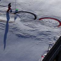 After heavy winds, a volunteer cleans the Olympic rings at the ski jumping venue. | REUTERS