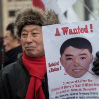 A South Korean protester holds a banner featuring the image of a mask worn by North Korean cheerleaders the previous day.
The protestors accused South Korean President Moon Jae-in of allowing North Korea to stage its \"propaganda\" in Seoul and undermining the military alliance with the US.  | AFP-JIJI