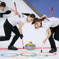 Yurika Yoshida (left), Chinami Yoshida (right) and Yumi Suzuki (rear) compete for Japan during the women\'s curling competition at the Pyeongchang Olympics. Japan defeated Denmark 8-5 on Thursday in Gangneung, South Korea. | KYODO