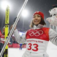 Bronze medalist Sara Takanashi celebrates on the podium alongside gold medalist Maren Lundby during the victory ceremony. | REUTERS