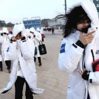 Staff from Olympic Park struggle to walk due to strong winds on Wednesday in Pyeongchang, South Korea. | REUTERS