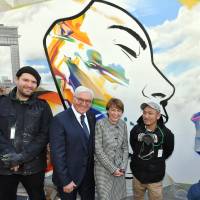 German President Frank-Walter Steinmeier (second from left) and his wife, Elke B&#252;denbender, pose for a photo alongside graffiti artists Justus Becker (left) and Imaone (right) at the launch of an art project titled \"German Embassy Berlin Wall Project\" at the German Embassy on Feb. 7. | YOSHIAKI MIURA