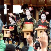 Maiko (apprentice geisha) throw small bags of beans to wish for sound health throughout the new year at a Setsubun festival at Yasaka Shrine in Kyoto on Friday. Setsubun, which means \"season time,\" is a celebration of the coming spring where beans are traditionally thrown to ward off bad spirits. | KYODO