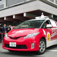 A self-driving vehicle leaves Japan Post Co.\'s headquarters in Tokyo\'s Kasumigaseki district for a demonstration on Wednesday. | KYODO