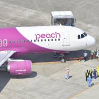 A Peach Aviation Ltd. passenger jet is towed by a truck after two of its tires went flat after landing at Fukuoka airport Saturday morning. | KYODO