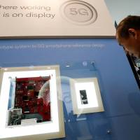 A display in the booth of Qualcomm shows the journey early 5G phone chipsets have made out of the lab, starting as a suitcase full of outsized prototype components (left), which has now been shrunk into a smartphone the size of a very thick chocolate bar (right), at Mobile World Congress in Barcelona, Spain, Feb. 27. | REUTERS
