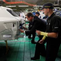 Then-British Prime Minister David Cameron installs a badge on a car at the Toyota factory in Burnaston, central England, in 2011. | REUTERS