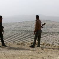 Turkish-backed Free Syrian Army fighters stand atop of mount Bafliyun, in the Afrin region of Syria Monday. | REUTERS