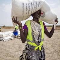 A local community volunteer carries a sack of seeds distributed by the International Committee of the Red Cross (ICRC) in the opposition-controlled town of Thonyor, in Leer county, South Sudan, last April. The wave of refugees fleeing crop failures, droughts and rising sea levels will grow drastically over the next three decades if world governments do not intervene, the World Bank warned Monday. By 2050, 143 million \"climate migrants\" will face an \"existential threat\" and be displaced, the World Bank said in a new report. | AFP-JIJI
