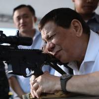 Philippine President Rodrigo Duterte fires a few rounds with a sniper rifle during the opening ceremony of the National Special Weapons and Tactics (SWAT) Challenge in Davao City, on the southern Philippine island of Mindanao, on March 1. | AFP-JIJI