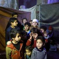 Syrian children pose for a picture in a basement being used as a make-shift bomb shelter in the rebel-held town of Douma in the eastern Ghouta enclave on the outskirts of Damascus on Thursday. | AFP-JIJI