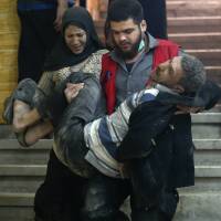 Syrian civilians arrive at a makeshift clinic during Syrian government airstrikes on Zamalka, in the rebel enclave of eastern Ghouta on the outskirts of Damascus, on Tuesday. | AFP-JIJI