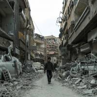 A Syrian child walks down a street past rubble from destroyed buildings in the rebel-held town of Douma in the eastern Ghouta enclave on the outskirts of Damascus Thursday. | AFP-JIJI