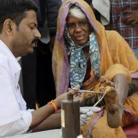 A doctor cleans the wound of a woman farmer at the end of her six-day march on foot, in Mumbai Monday. | AP