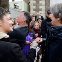British Prime Minister Theresa May (right) \"fist-bumps\" a member of the public during her visit to Salisbury, southern England, on Thursday, where she visited the areas where former Russian doubleagent Sergei Skripal and his daughter, Yulia, went to, and were discovered at, following an apparent nerve agent attack on March 4. | AFP-JIJI