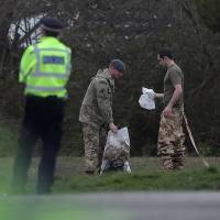 A British police officer stands on duty as members of the Army work in a residential street in Alderholt, southern England, on Thursday as investigations and operations continue in connection with the major incident sparked after a man and a woman were apparently poisoned in a nerve agent attack in Salisbury on March 4. | AFP-JIJI