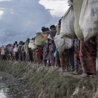Rohingya refugees walk after crossing the Naf river from Myanmar into Bangladesh in Whaikhyang in October. Myanmar is continuing its \"ethnic cleansing\" of the Rohingya with a \"campaign of terror and forced starvation\" in Rakhine state, a U.N. human rights envoy said on March 6, six months after a military crackdown sparked a mass exodus of the Muslim minority. | AFP-JIJI