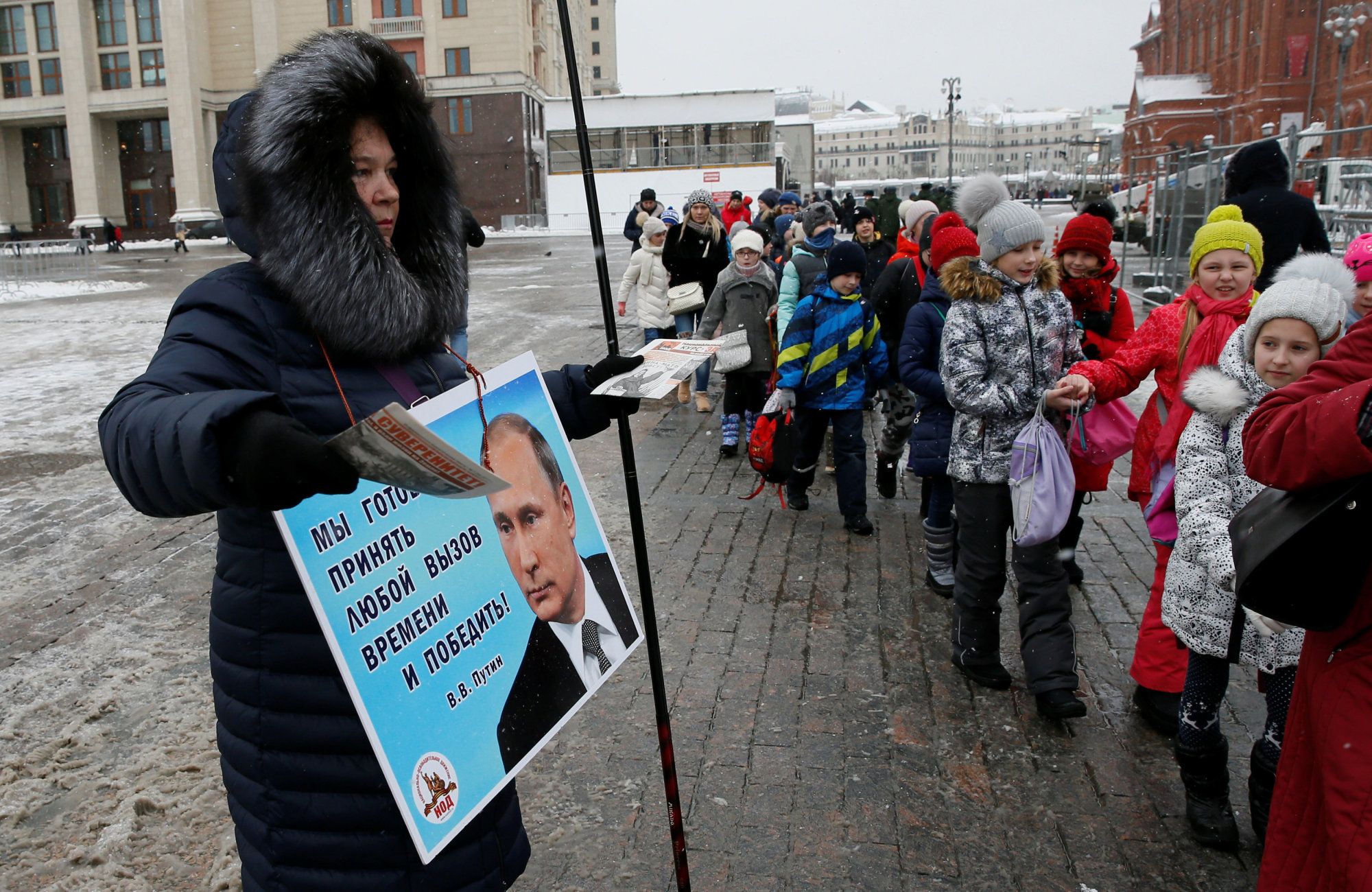 An activist distributes electoral materials in support of presidential candidate President Vladimir Putin in central Moscow on Thursday. The placard reads: 'We are ready to take any challenge of time and win V.V. Putin.' | REUTERS