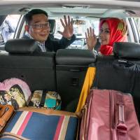 Bandung Major Ridwan Kamil, who is front-runner to become governor of West Java province but has been targeted by online hoax stories labeling him an infidel, waves with his wife, Atalia Kamil, to reporters from his car in Bandung on Jan. 20. | REUTERS