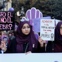 People march during a demonstration as part of a nationwide feminist strike on International Women\'s Day in Valencia, Spain, Thursday. A placard (left) reads \"I cover my hair, not my brain.\" | REUTERS