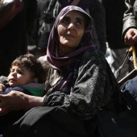 A Syrian woman and a child are seen in the village of Qalaat al-Madiq, some 45 kilometers northwest of the central city of Hama, on Monday, as evacuations from eastern Ghouta continue following a deal that was announced earlier in the week. | AFP-JIJI